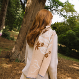 Person wearing a beige floral-patterned shawl in a park setting