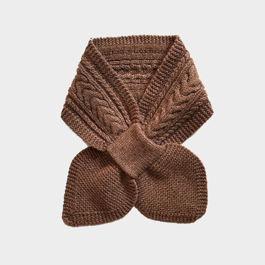 A brown cable-knit scarf folded and tied in a bow, displayed on a light gray background.