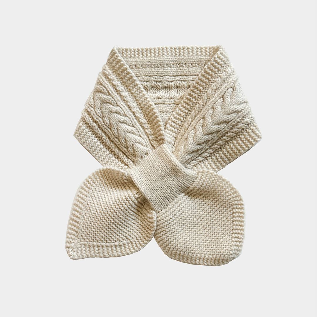 A cream-colored cable-knit scarf with a matching knitted wristlet or wristband, displayed on a light gray background.