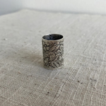 Silver embossed slider on a textured fabric surface
