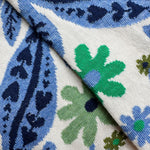 A close-up socks with a blue, green, and navy floral and paisley pattern on a white background.