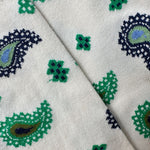 Close-up of socks with a cream base and a repeating paisley and floral pattern in green, navy blue, and light blue.
