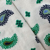 Close-up of socks with a cream base and a repeating paisley and floral pattern in green, navy blue, and light blue.