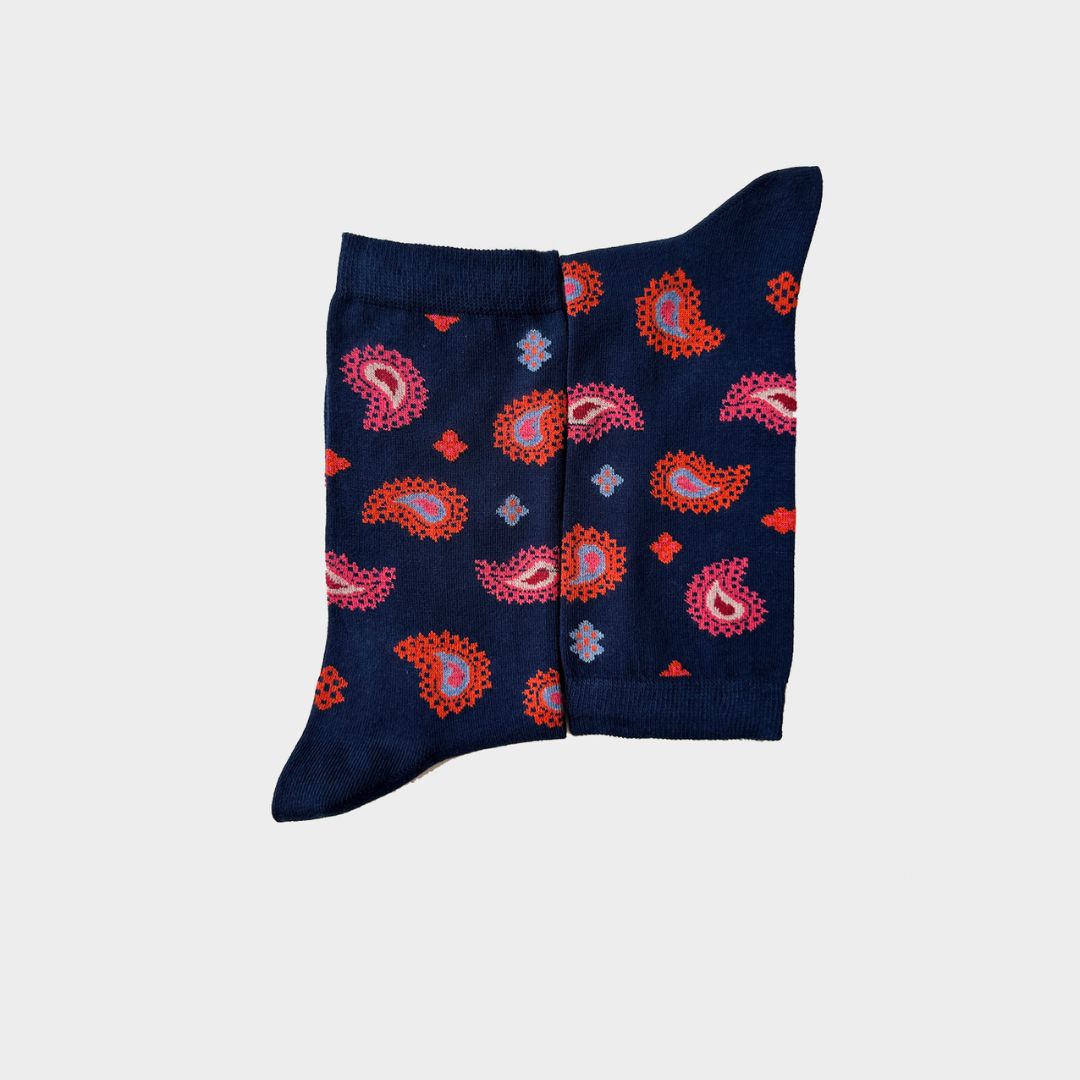 A pair of navy blue crew socks with a vibrant paisley pattern in pink, orange, and light blue, displayed flat against a light gray background.