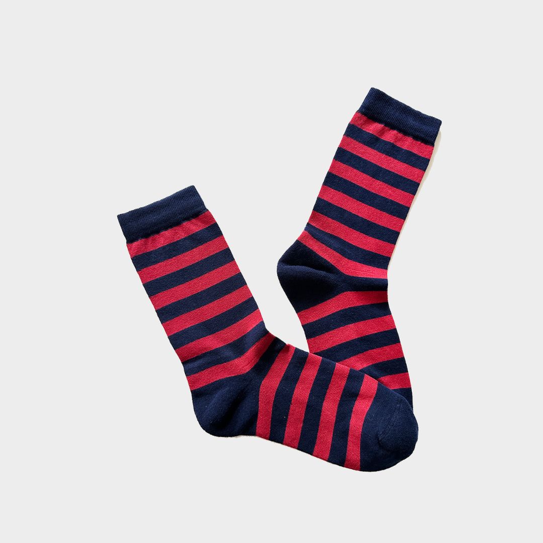 A pair of crew socks with alternating horizontal stripes of dark navy blue and bright red, displayed against a light gray background.