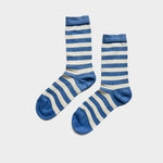 A pair of crew socks with horizontal blue and cream stripes, featuring solid blue toes and heels, displayed against a light gray background.