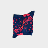 A pair of navy blue socks with a vibrant pink botanical and floral pattern, displayed flat against a light gray background.