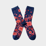 A pair of navy blue crew socks with a vibrant coral pink floral pattern, displayed in an X-shaped arrangement on a light gray background.
