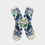 A pair of cream-colored crew socks with a blue and green botanical pattern, displayed in a crossed arrangement against a light gray background.
