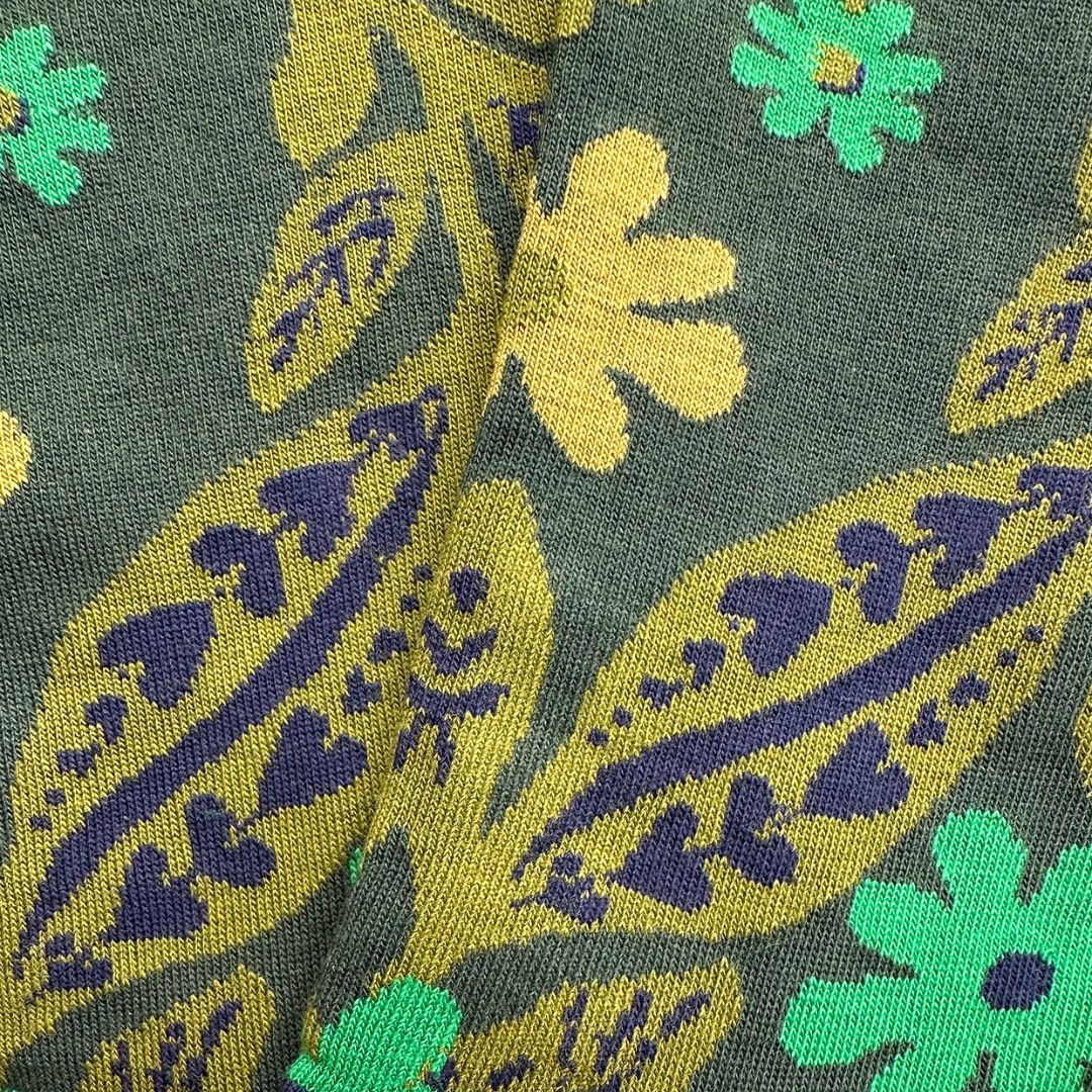 A close-up of socks with a retro floral and paisley pattern in olive green, mustard yellow, and dark purple.