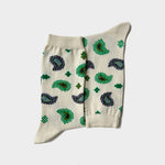 A pair of cream-colored crew socks with a green and black paisley pattern, laid flat against a light gray background.