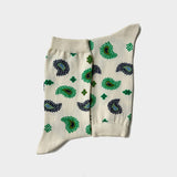 A pair of cream-colored crew socks with a green and black paisley pattern, laid flat against a light gray background.