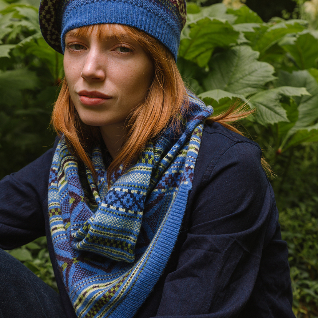 Person wearing a blue knitted hat and scarf in a natural setting