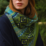 Person wearing a green and blue patterned scarf with a blurred natural background