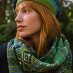 Woman wearing a green and blue patterned hat and scarf against a blurred natural background