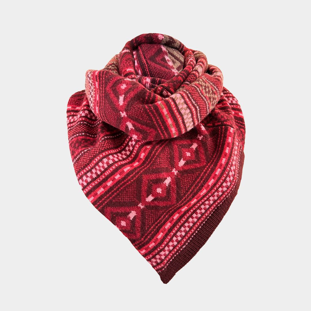 A red patterned knit scarf with geometric and tribal-inspired designs, folded and displayed on a light gray background.