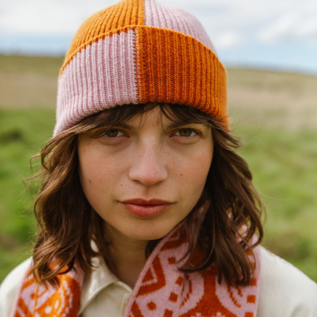 Person wearing a colorful knit hat and scarf in a natural setting