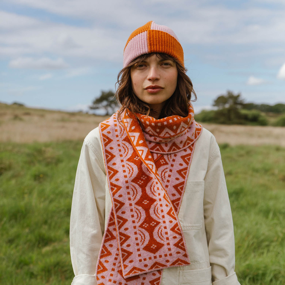 Woman wearing a patterned scarf and hat in a field
